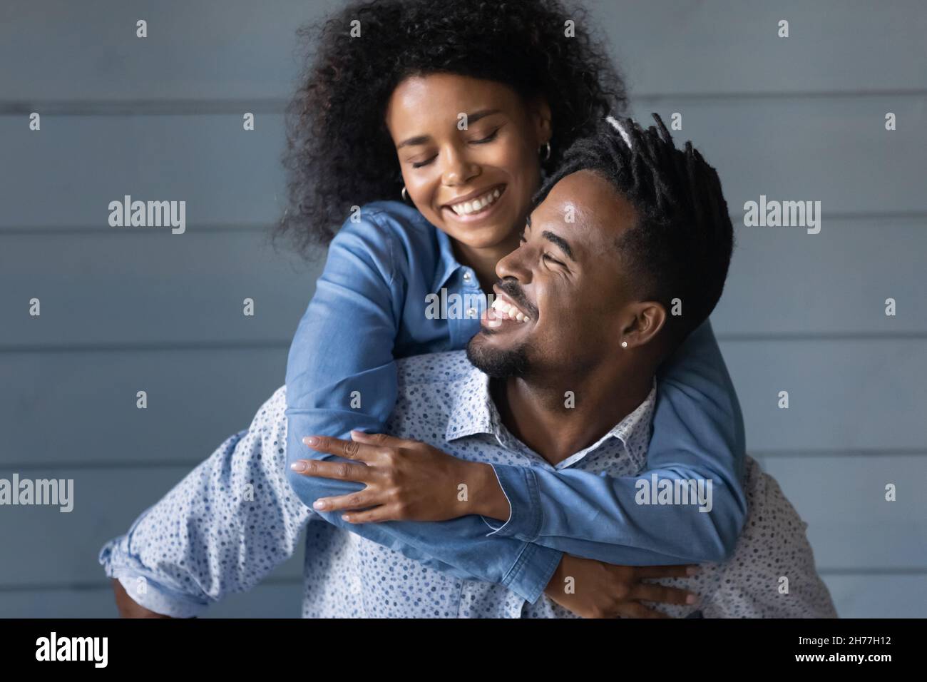 Felice giovane uomo di etnia brasiliana che dà cavalcata di piggyback alla moglie. Foto Stock