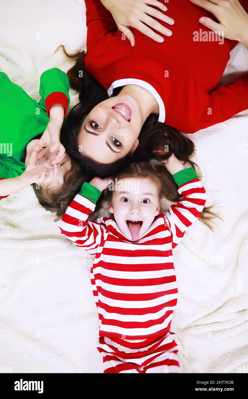 Una famiglia in pigiama a righe sta riposando a casa. Bambini piccoli  vestiti come elfi sono stesi sul divano. Una famiglia felice Foto stock -  Alamy