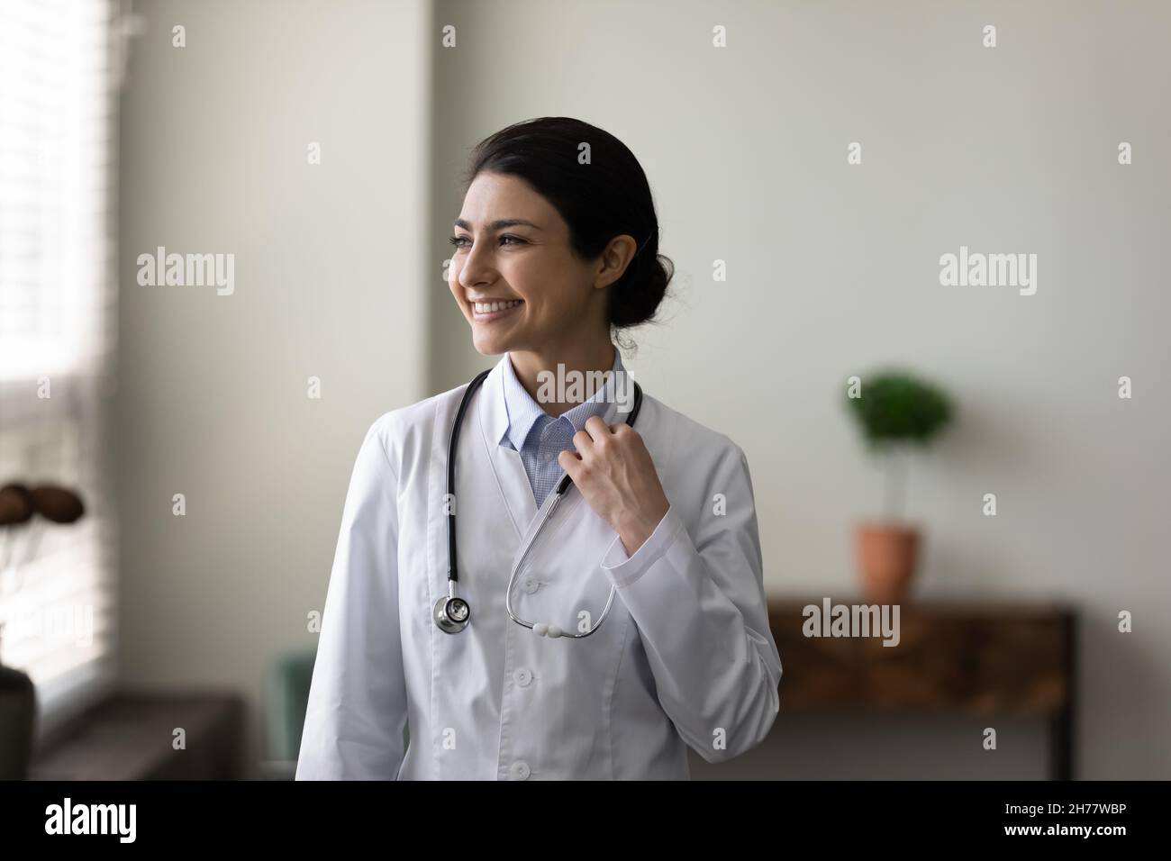 Testa girato sognante sorridente medico indiano femmina guardando a distanza Foto Stock