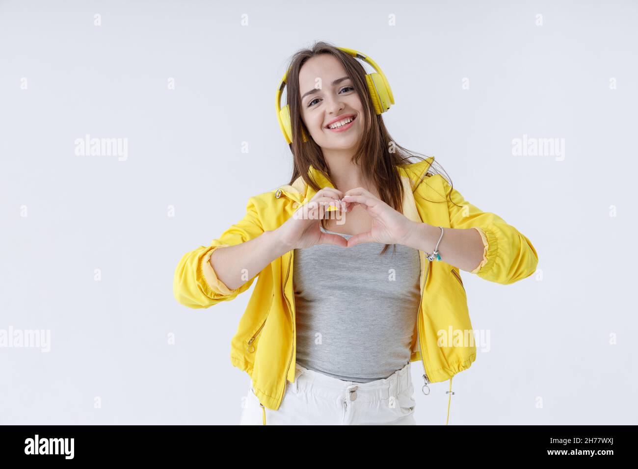 Bella giovane donna in cuffia che mostra il segno del cuore Foto Stock