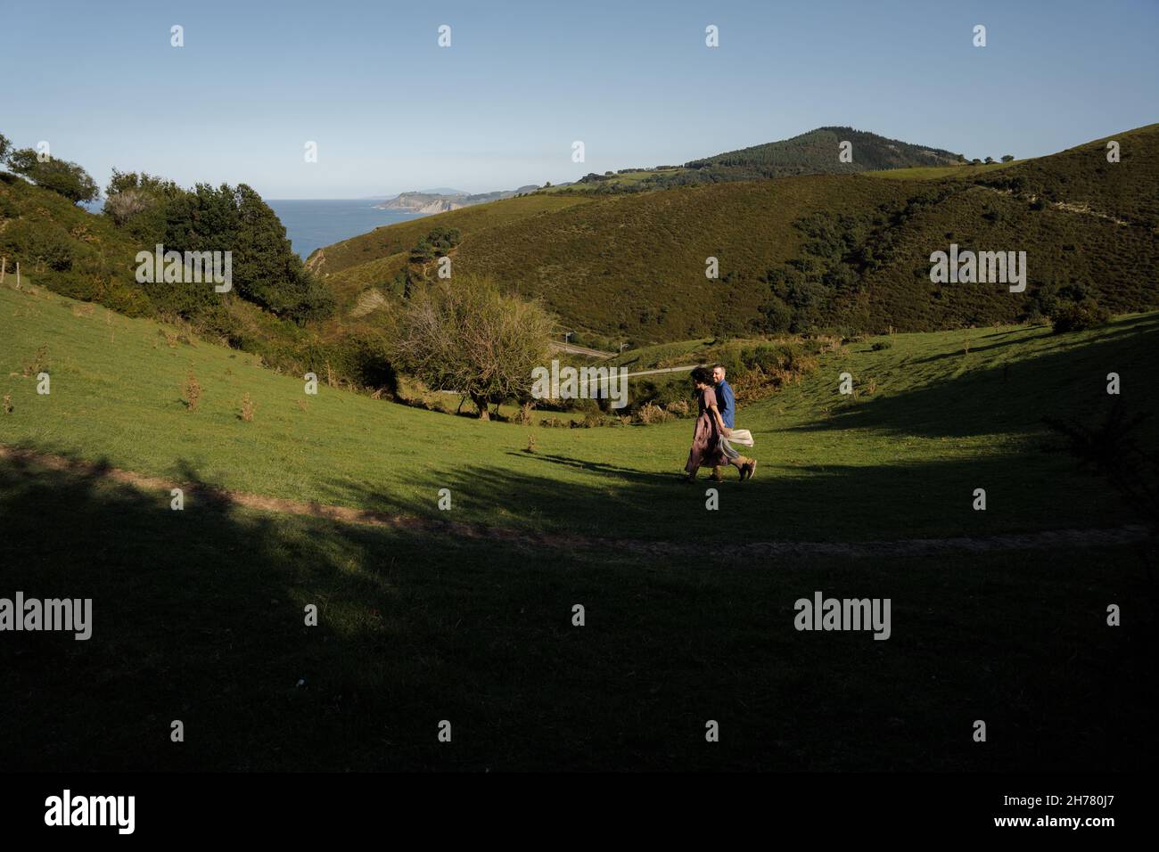 Una giovane coppia carina che cammina su una collina verde Foto Stock
