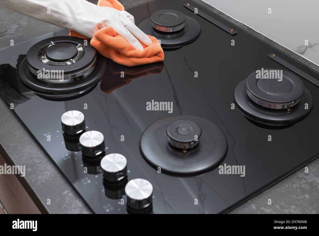 Stufa a gas di pulizia. Persona lucidatura a mano del vetro con microfibra Foto Stock