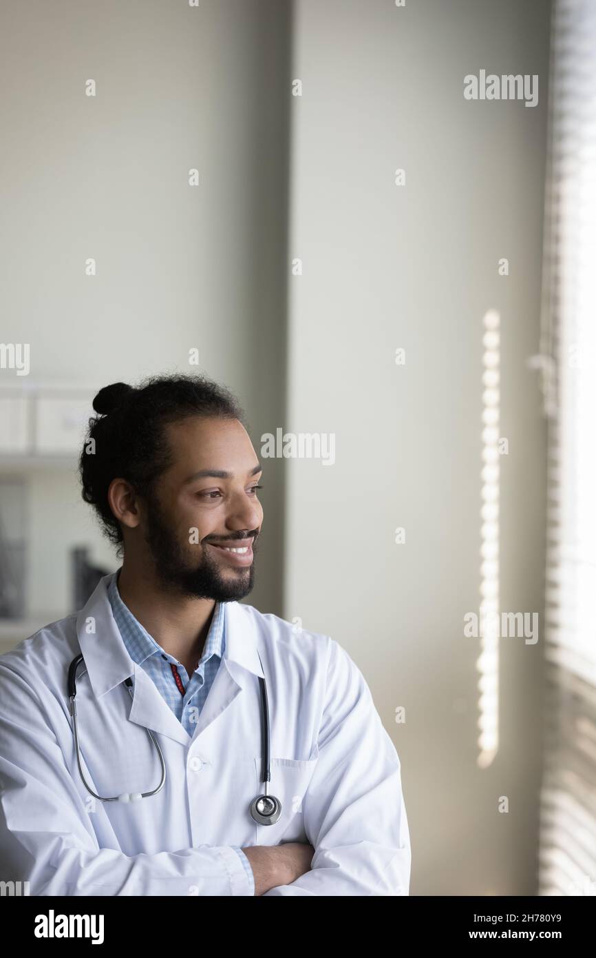 Foto verticale sorridente medico afroamericano che guarda a distanza Foto Stock