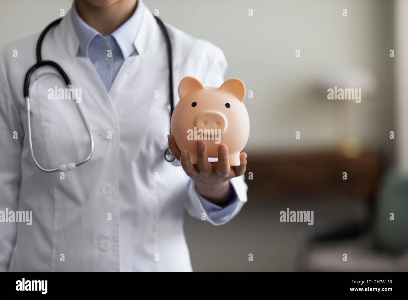 Crop close up medico femmina tenendo rosa Piggy banca Foto Stock