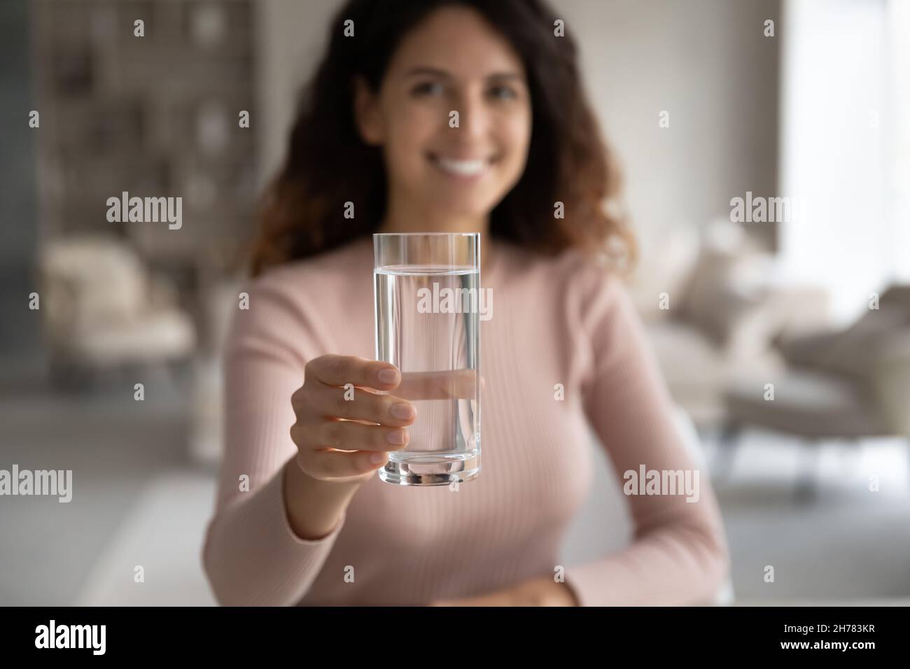 Primo piano mettere a fuoco su vetro di acqua nella mano femminile Foto Stock