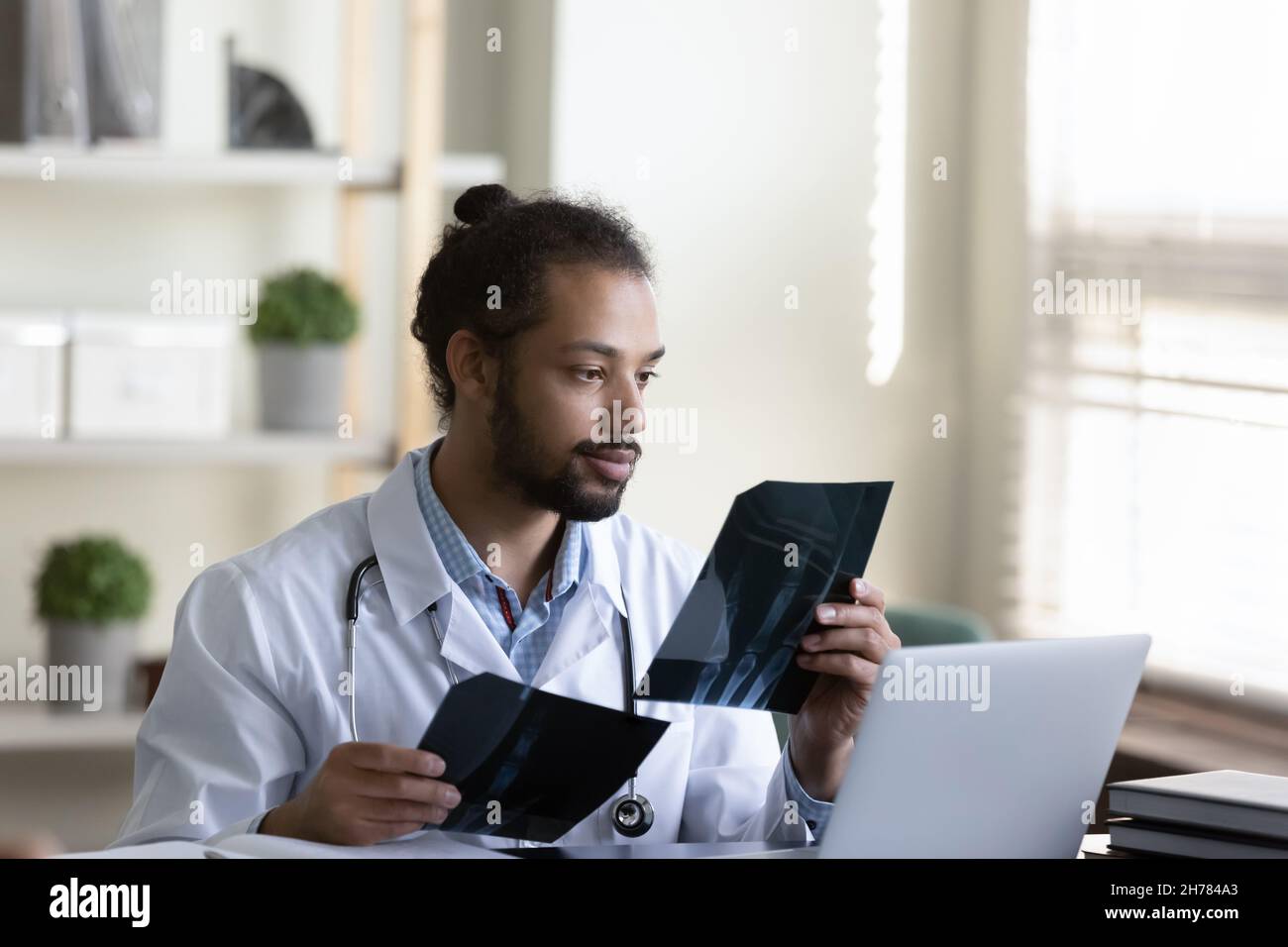 Medico chirurgo africano americano che tiene le immagini di raggi X. Foto Stock