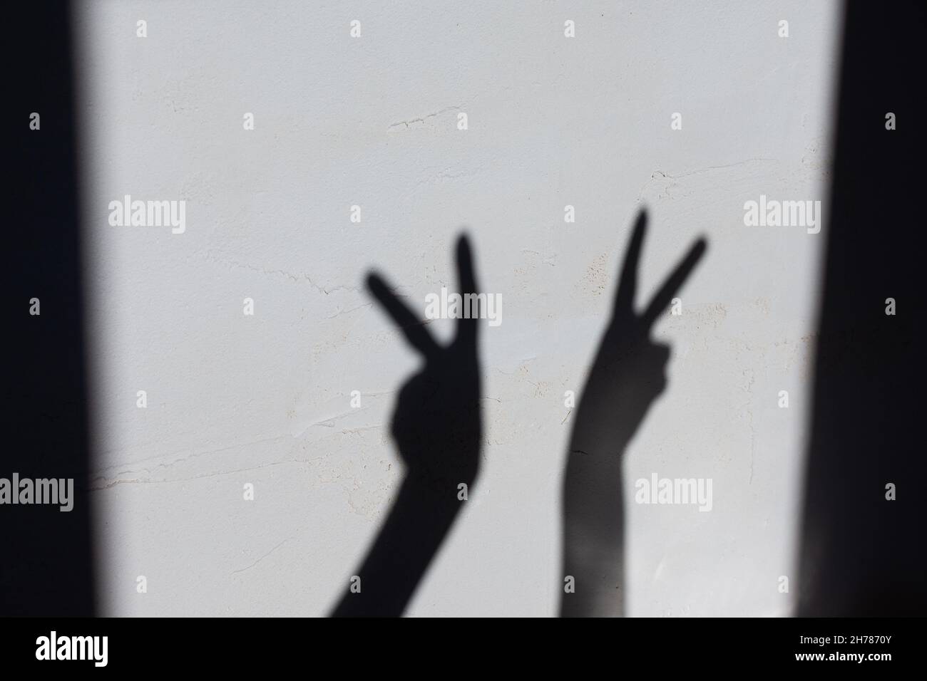 Ombra dalle mani femminili su un muro di cemento, le mani mostrano il segno di victorie Foto Stock
