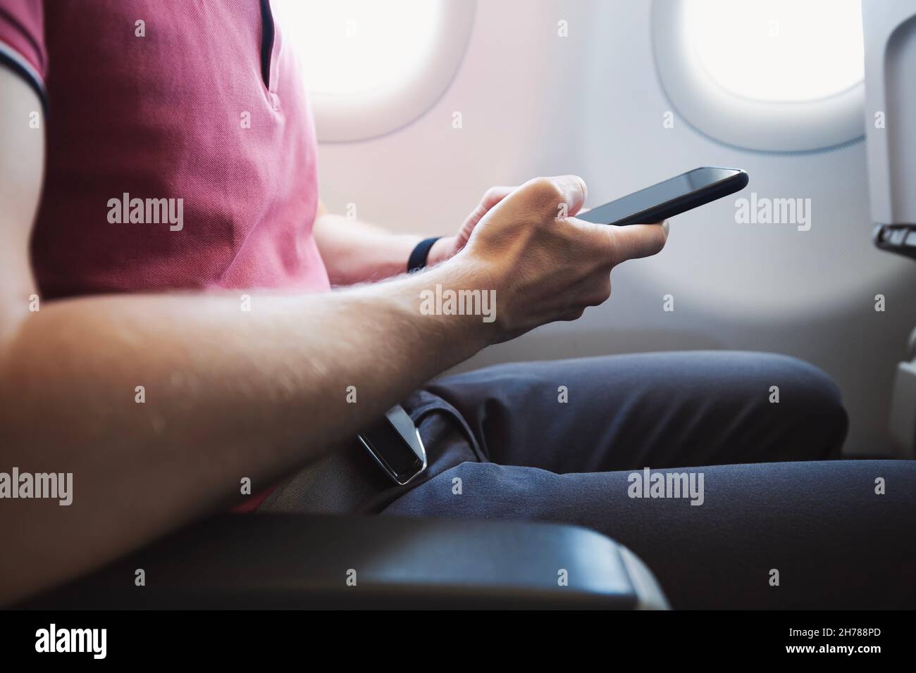 Mani che tengono lo smartphone in aereo. Passeggero che utilizza la connessione Internet durante il volo. Foto Stock