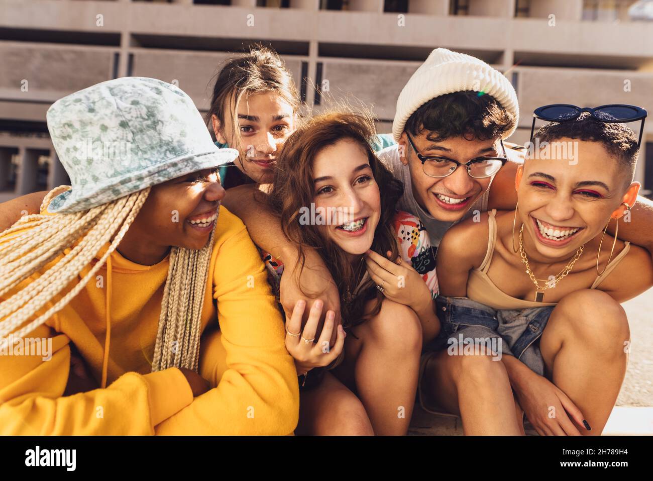 Trascorrere bei momenti con gli amici. Gruppo di amici di generazione z ridere allegro mentre si aggrappano insieme all'aperto in città. Buon giovane frien Foto Stock