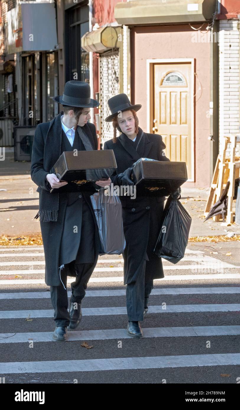 Due ebrei ortodossi hasidici che camminano sulle scatole di trasporto di Lee Ave. venerdì pomeriggio a Williamsburg, Brooklyn, New York. Foto Stock