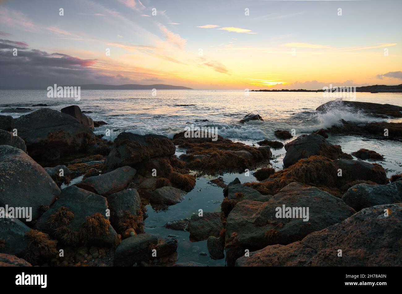 Splendido paesaggio marino al tramonto della costa rocciosa sulla strada atlantica selvaggia a Barna, Galway, Irlanda Foto Stock