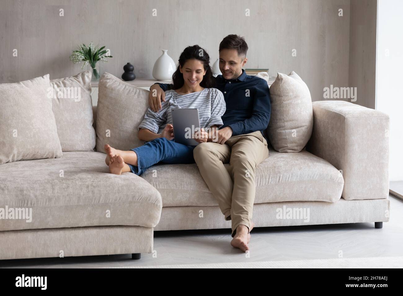 Coppia rilassante sul divano in soggiorno con tablet digitale Foto Stock