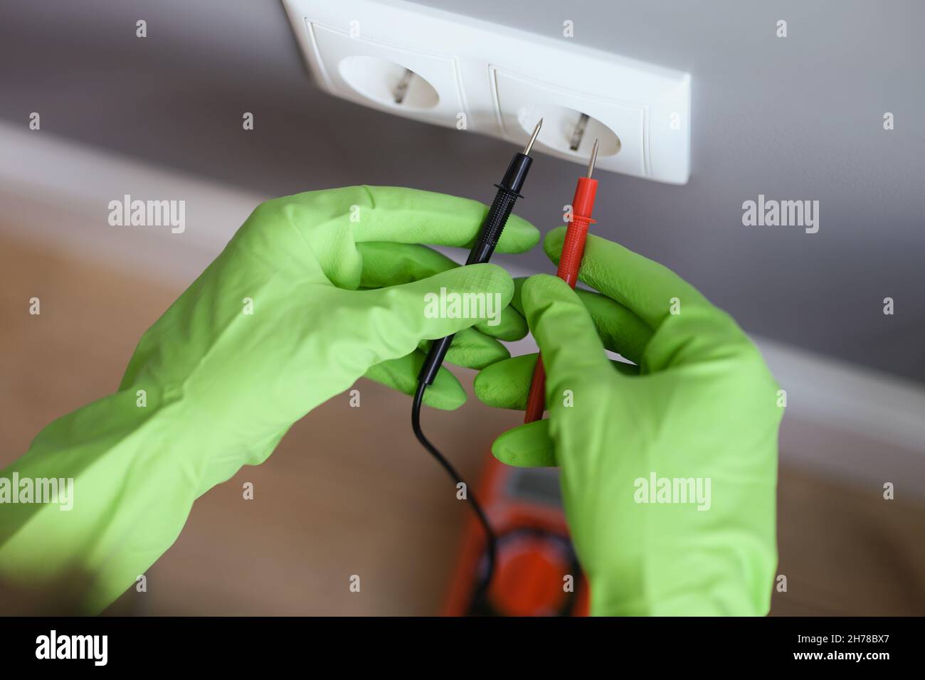 Misurazione della tensione con un multimetro, indossare guanti di gomma Foto Stock