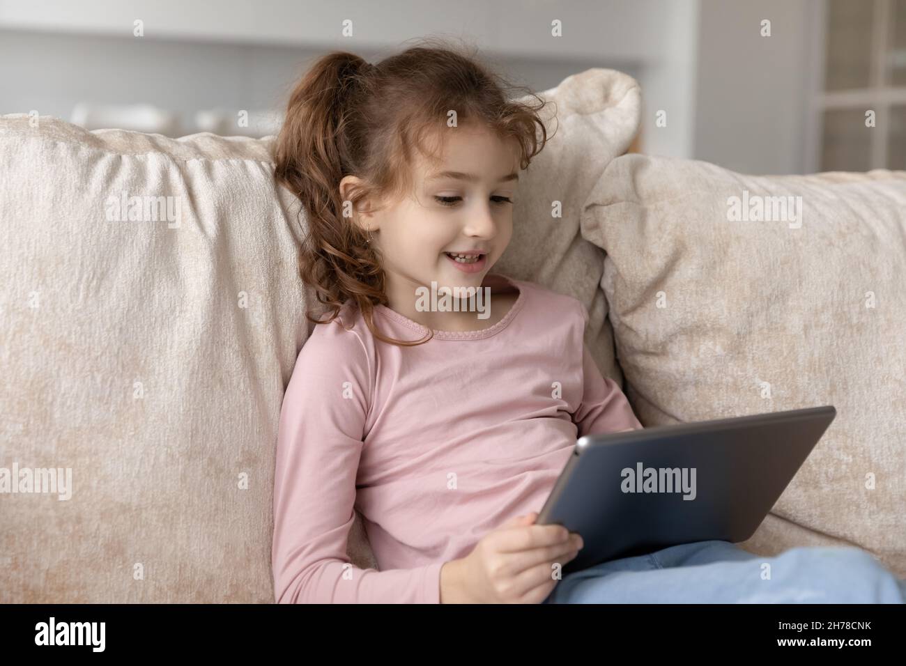 Primo piano adorabile ragazza carina bambino utilizzando tablet a casa Foto Stock