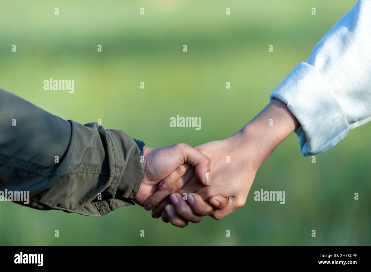 Indonesiano maschio e femmina che tiene la mano insieme su sfondo sfocato natura. Foto Stock