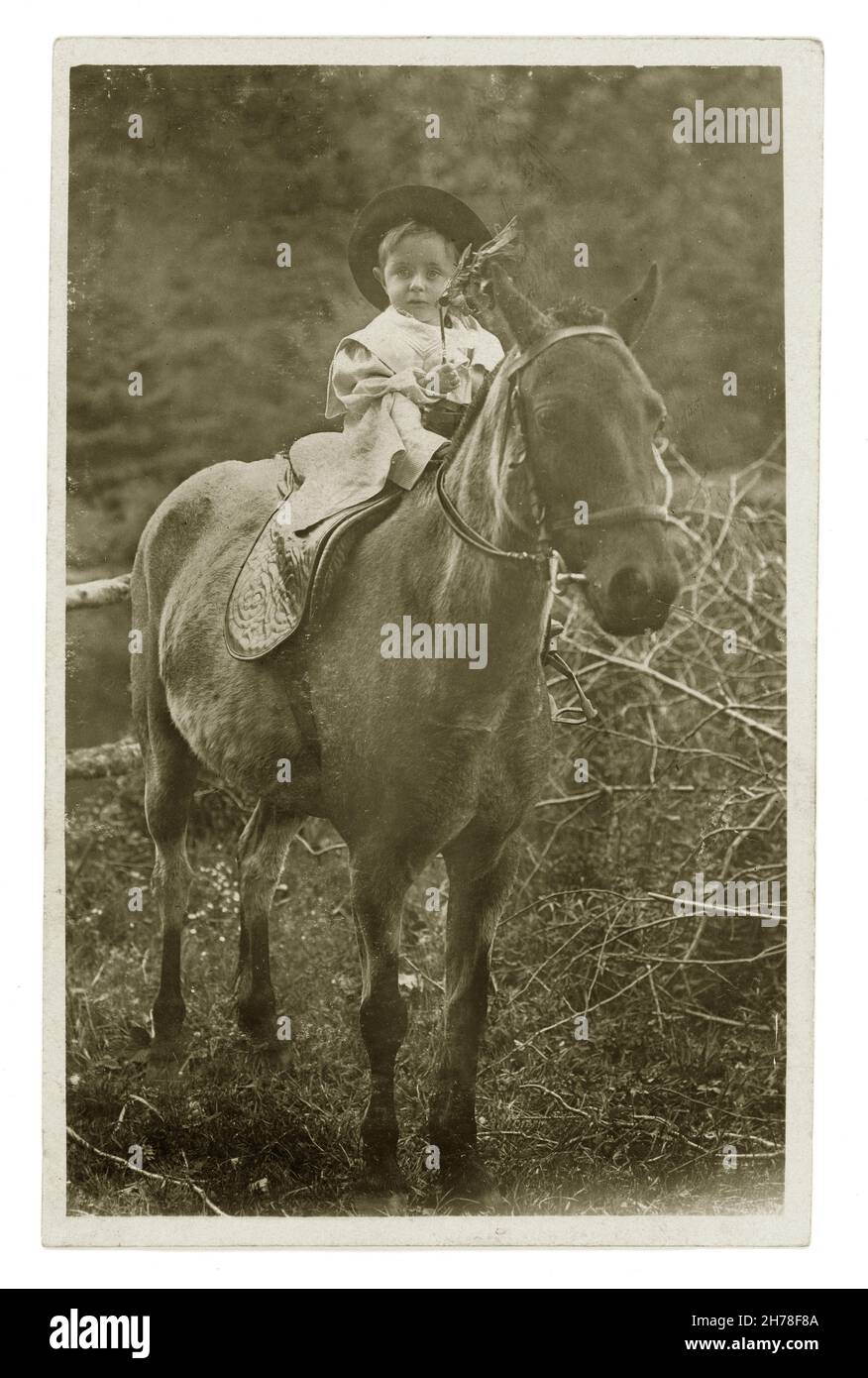 Cartolina del primo 1900 di bambino seduto su un cavallo, con sorella che tiene reins, Llandygwydd, Cardiganshire, Galles, Regno Unito circa 1909. Foto Stock