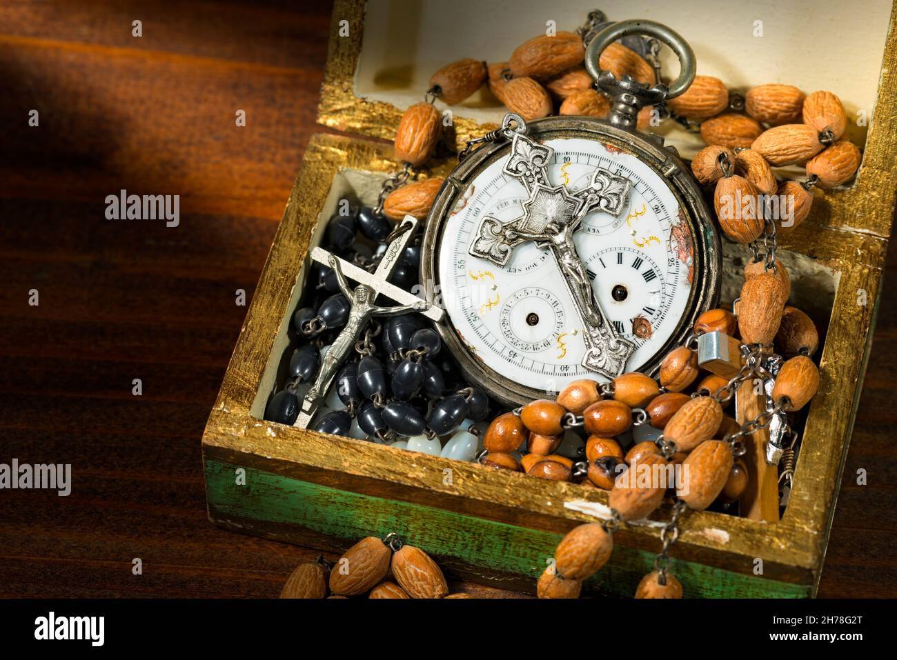 Tempo di pregare - aprire una scatola di legno piena di perle rosarie, crocefissi e un vecchio orologio tascabile con un crocifisso d'argento d'epoca Foto Stock