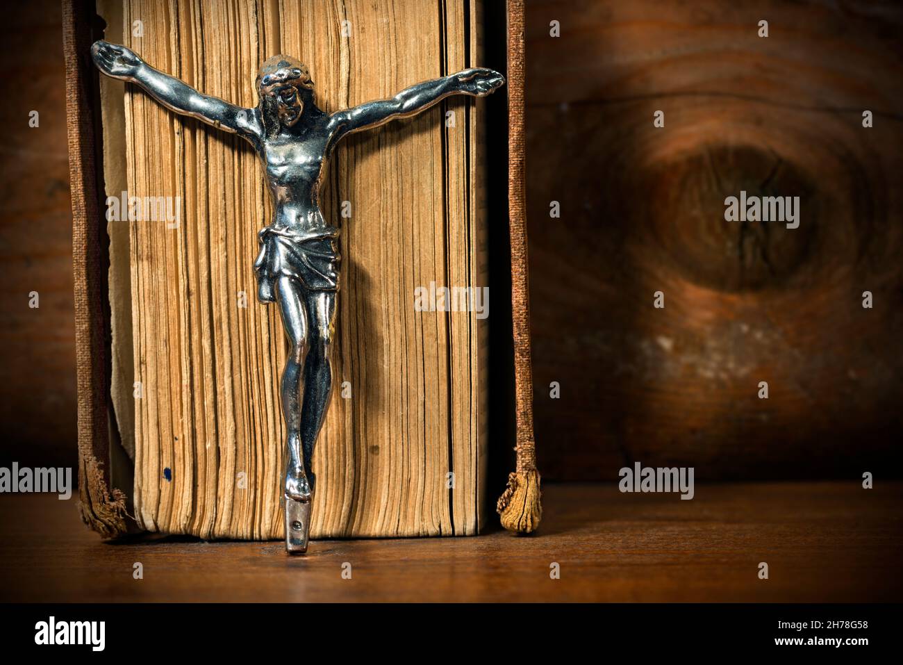 Primo piano di un crocifisso d'argento senza croce con una vecchia Bibbia  Santa. Su un tavolo di legno con ombre scure Foto stock - Alamy