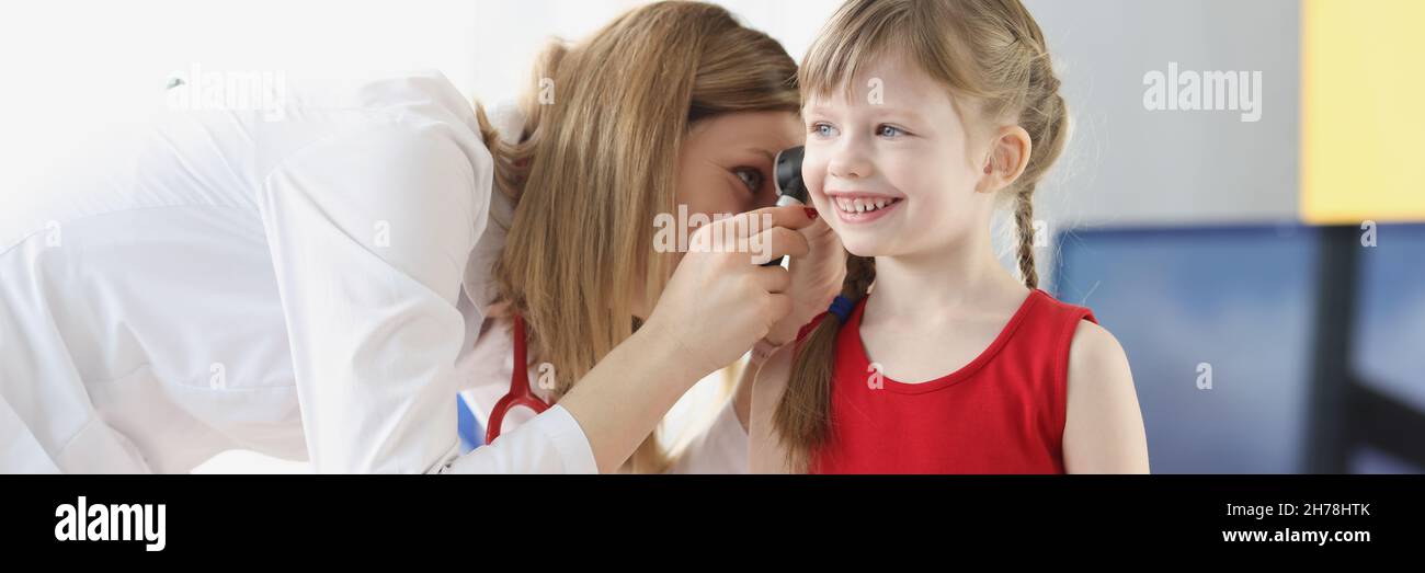 Donna pediatra esame orecchio di bambina con otoscopio in clinica Foto Stock