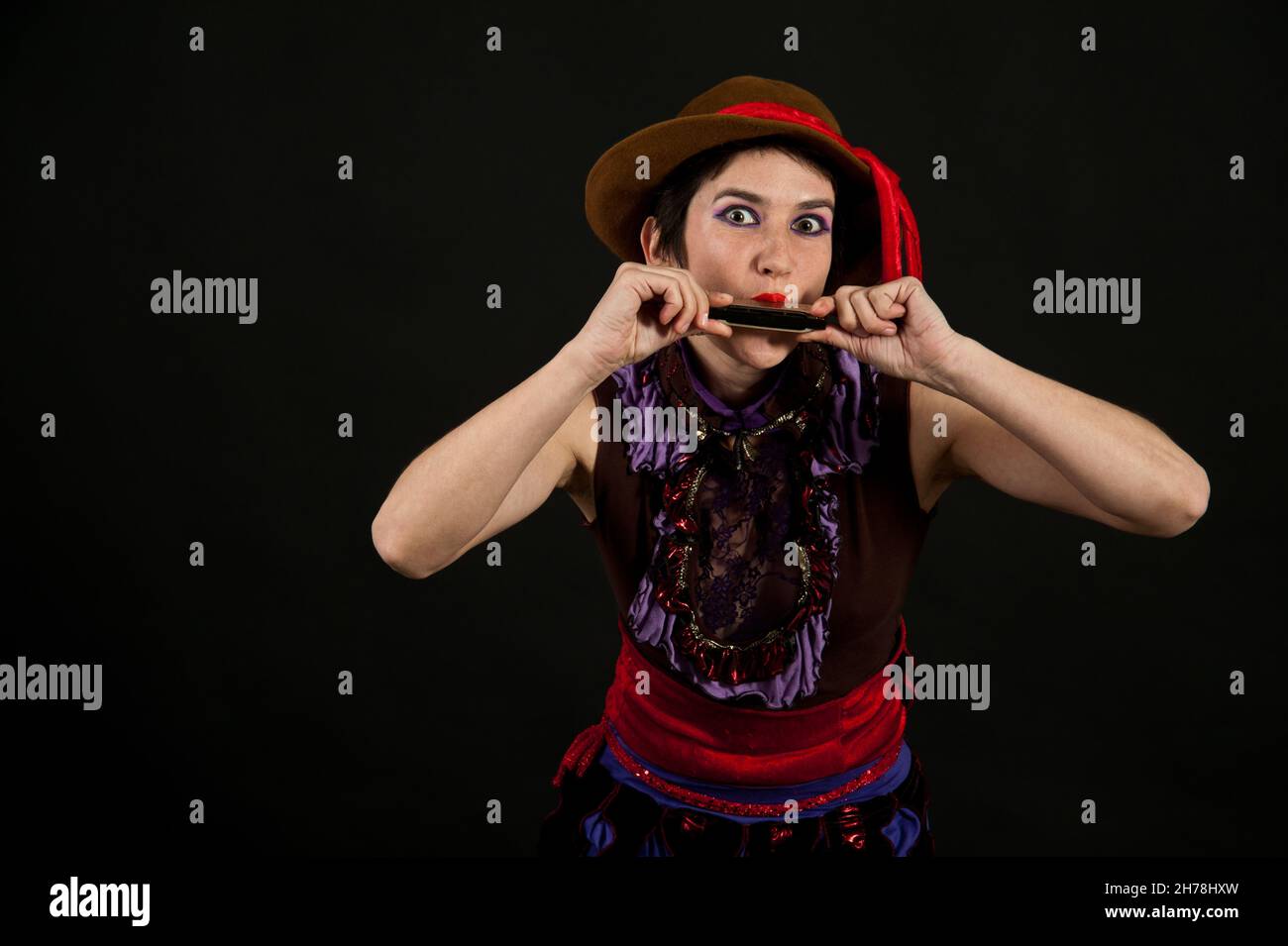 Stranamente vestita giovane donna suona l'armonica Foto Stock