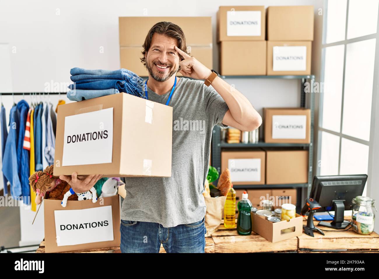 Bell'uomo di mezza età che tiene casella donazioni per la carità a volontario stare sorridente puntando a testa con un dito, grande idea o pensiero, buon Mem Foto Stock