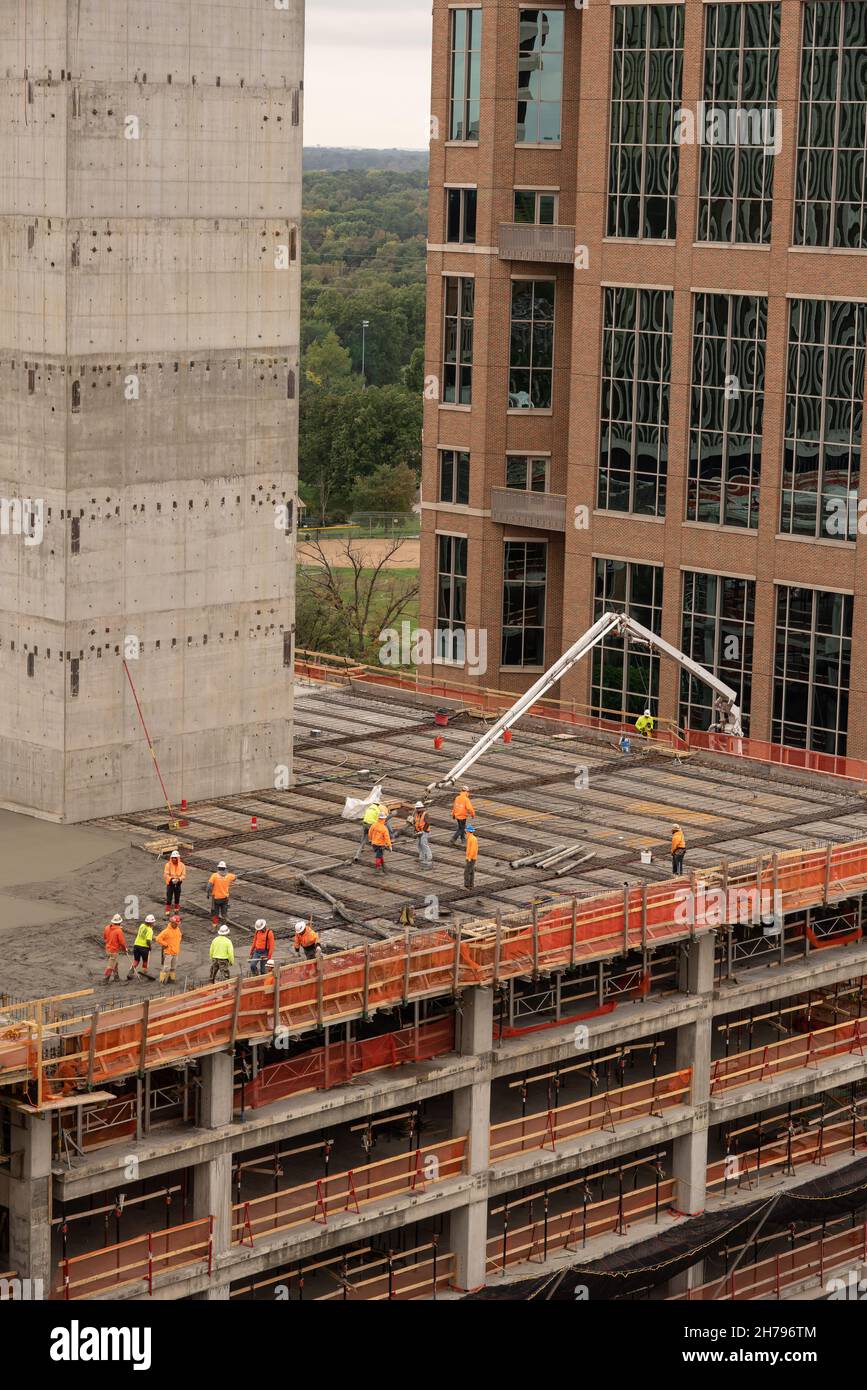 Un equipaggio di costruzioni versa calcestruzzo in un cantiere di lavoro del distretto commerciale. L'edificio è in costruzione a Clayton, MO, un sobborgo di St. Louis, MO, USA. Foto Stock
