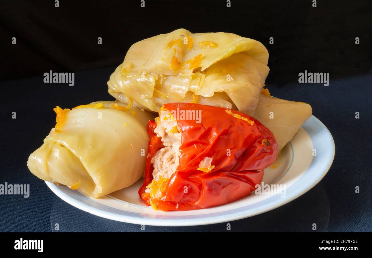 Peperoni e involtini di cavolo ripieni su un piatto. Cibo su sfondo nero Foto Stock