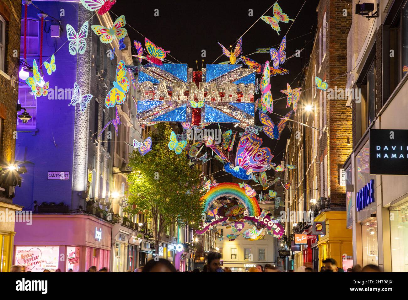 LONDRA, UK - 20 NOVEMBRE 2021: Viste lungo Carnaby Street a Londra a Natale mostrando le decorazioni e fuori dei negozi. Le persone possono essere viste all'esterno Foto Stock