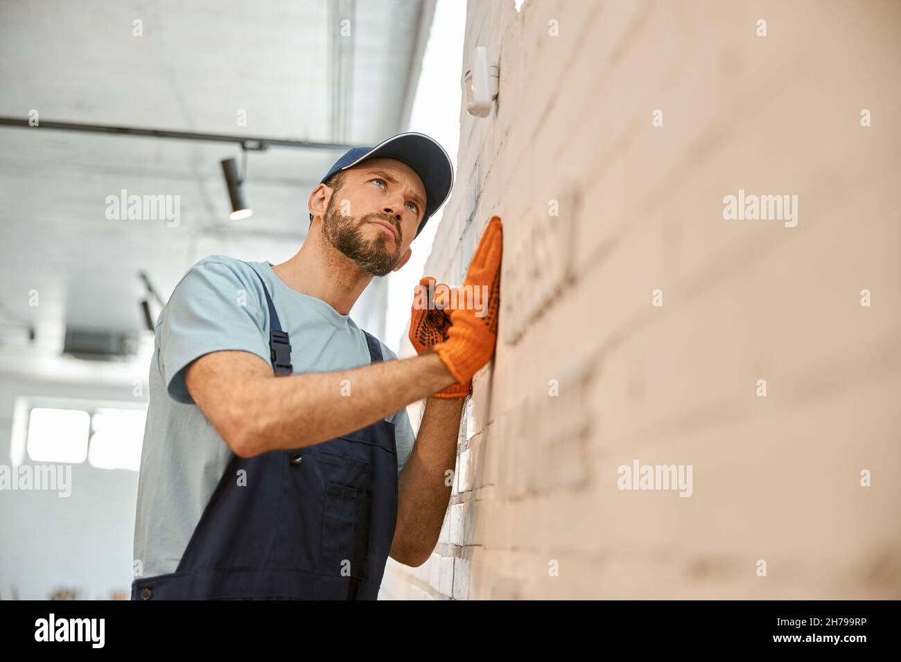 Lavoratore di sesso maschile che controlla la telecamera di sicurezza sulla parete Foto Stock