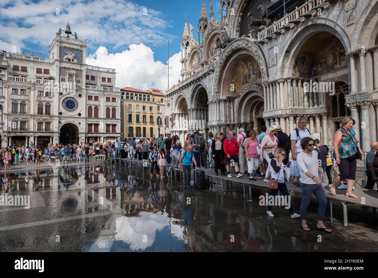 I turisti in tavola sopraelevata mantengono i piedi asciutti e fuori dalle acque di alluvione di fronte alla Basilica di San Marco, Venezia, Italia. Foto Stock