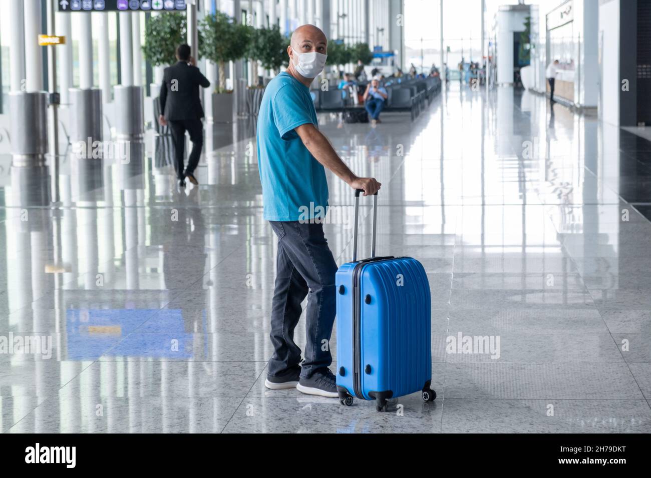 ISTANBUL, TURCHIA - 7 settembre 2021: Uomo che tira la valigia nel terminal dell'aeroporto di Istanbul e si guardò intorno. Ragazzo in viaggio che indossa abiti casual e. Foto Stock