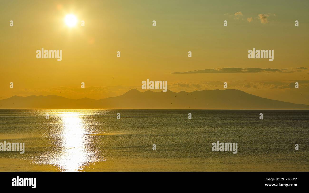 Tramonto d'oro sull'isola di Kunashir. L'isola giapponese Hokkaido è di fronte all'orizzonte. Territori contesi tra Russia e Giappone. Foto Stock