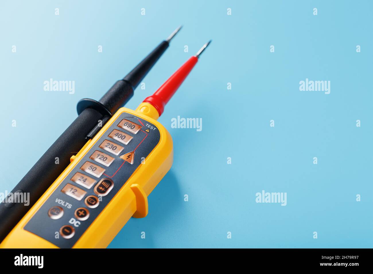 Indicatore di tensione giallo su sfondo blu. Spazio libero Test e verifica delle reti elettriche Foto Stock