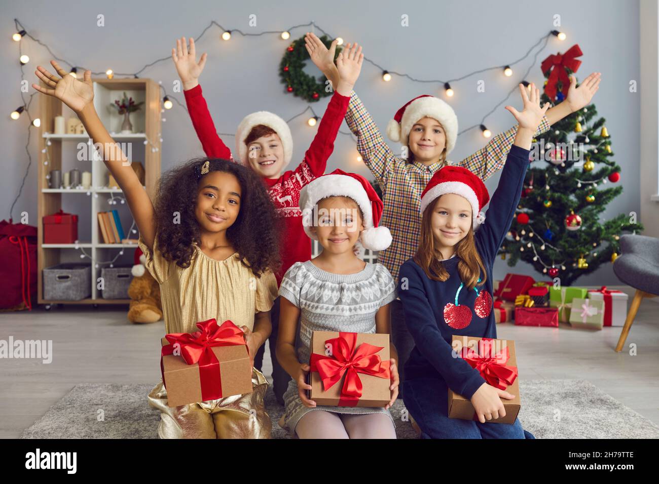 Sorridendo i bambini con regali che guardano la macchina fotografica durante la festa di Natale a casa Foto Stock