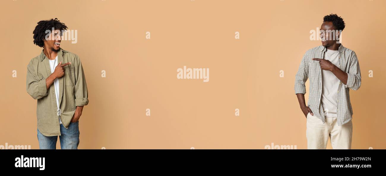 Controllare. Due allegre guys neri che puntano in mezzo a sfondo beige Foto Stock