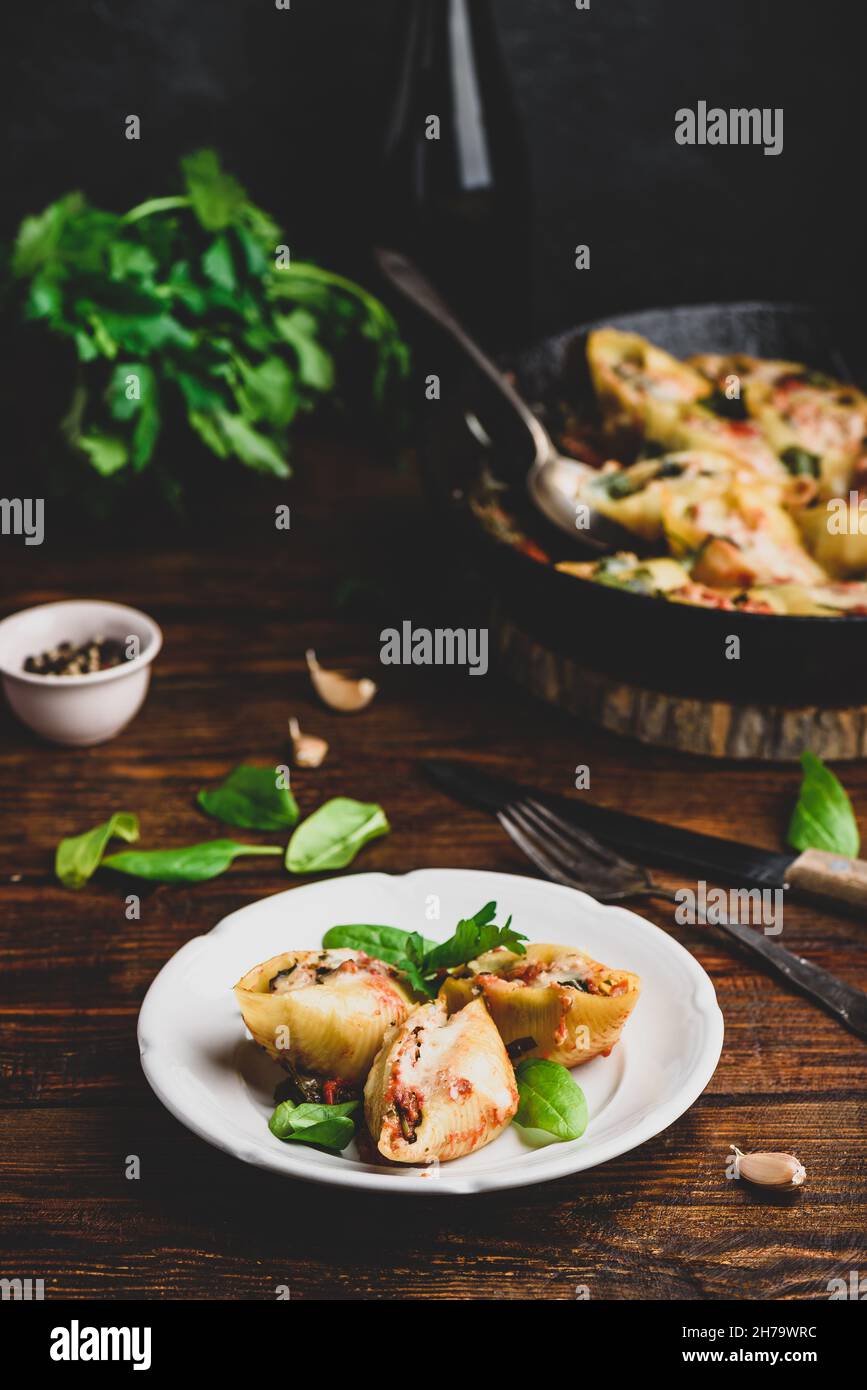 Conchiglie al forno farcite con manzo macinato, spinaci e formaggio su piatto bianco Foto Stock