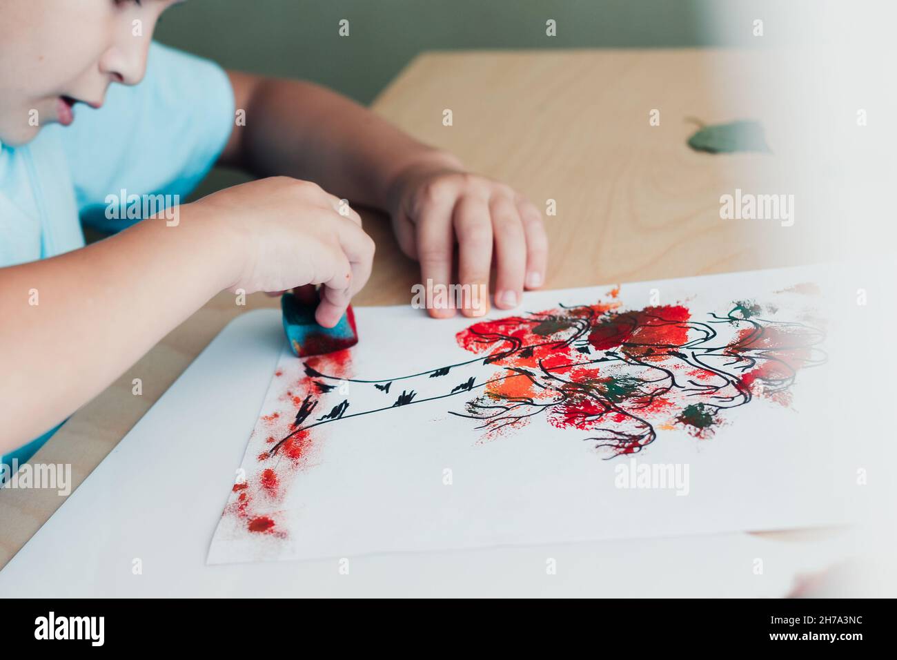 Primo piano di bambino che fa l'immagine da foglie di betulla asciutte. Ragazzo con spugna per dipingere le foglie. Attività autunnali per bambini Foto Stock