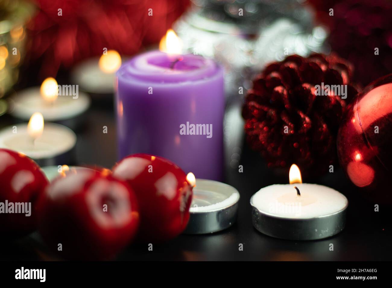 Candele illuminate con ornamenti natalizi come Baubles Cone Cone Cherries Pine e pelliccia rossa in background. Tema per buon Natale e Felice anno nuovo Foto Stock