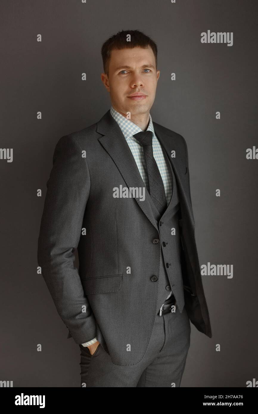 Un giovane uomo elegante in abito grigio e cravatta su sfondo grigio. Stile  aziendale. Immagine alla moda. Giovane uomo d'affari in un abito elegante e  cravatta Foto stock - Alamy