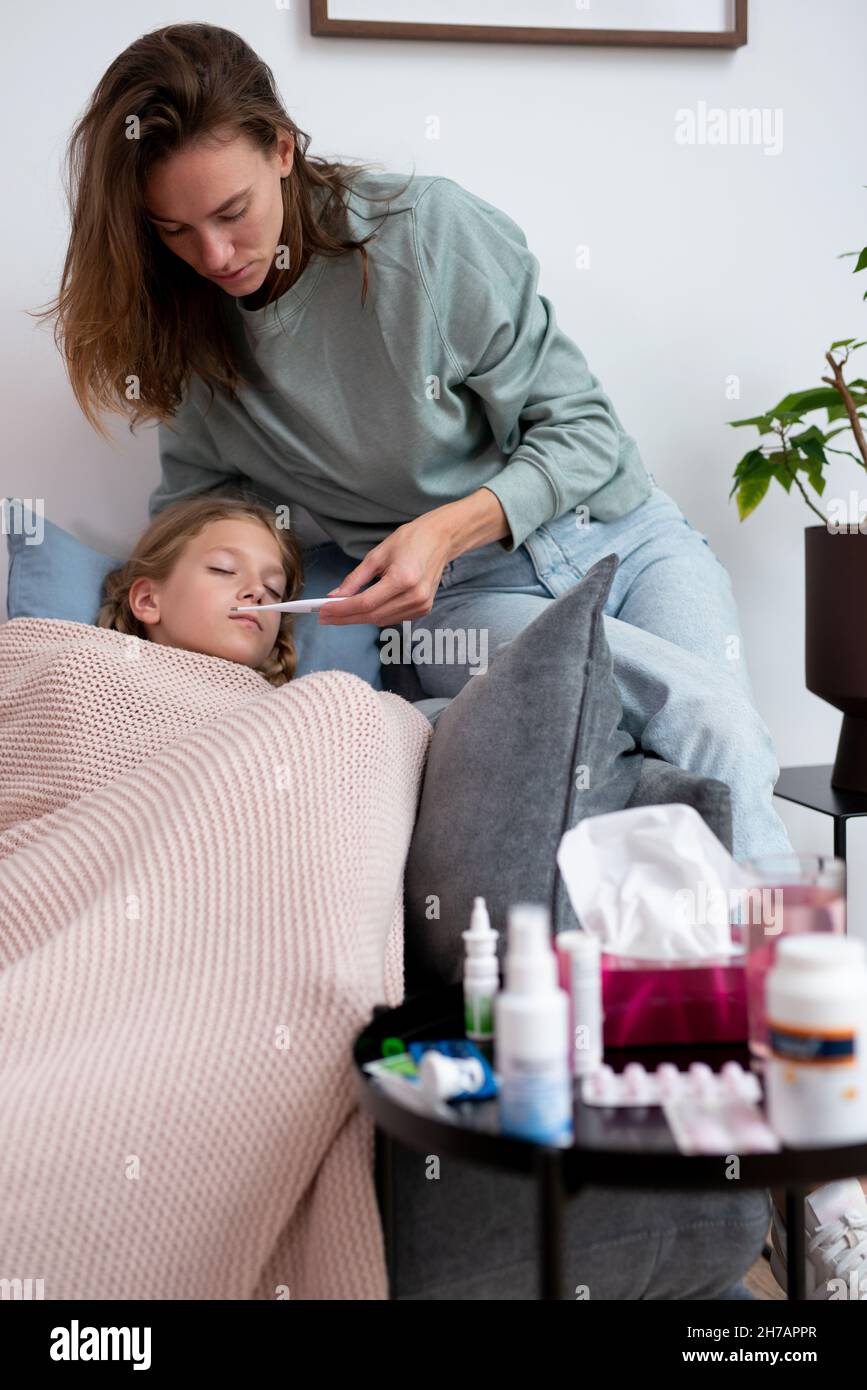 Una madre con un termometro sta andando prendere la temperatura del suo bambino. Foto Stock