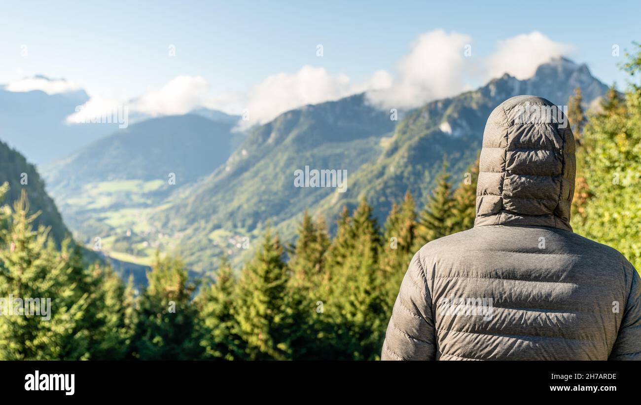 Paesaggio di montagna con una persona sulla schiena con una giacca in giù e cappuccio su Foto Stock