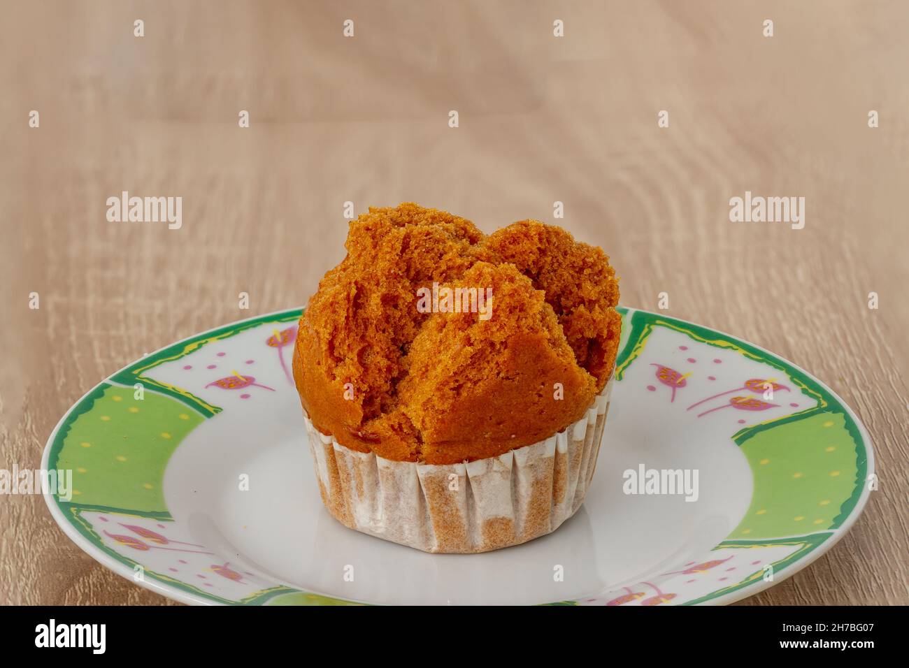 Un pan di Spagna su un piccolo piatto per la colazione e un amico per bere caffè, sfondo di legno Foto Stock