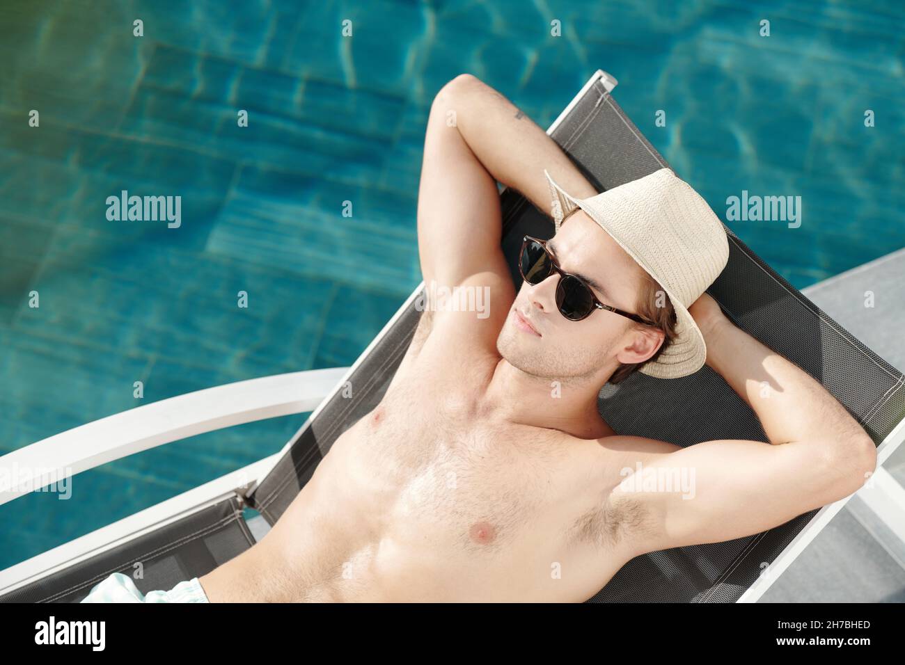 Il giovane si rilassa in piscina nella soleggiata giornata estiva Foto Stock