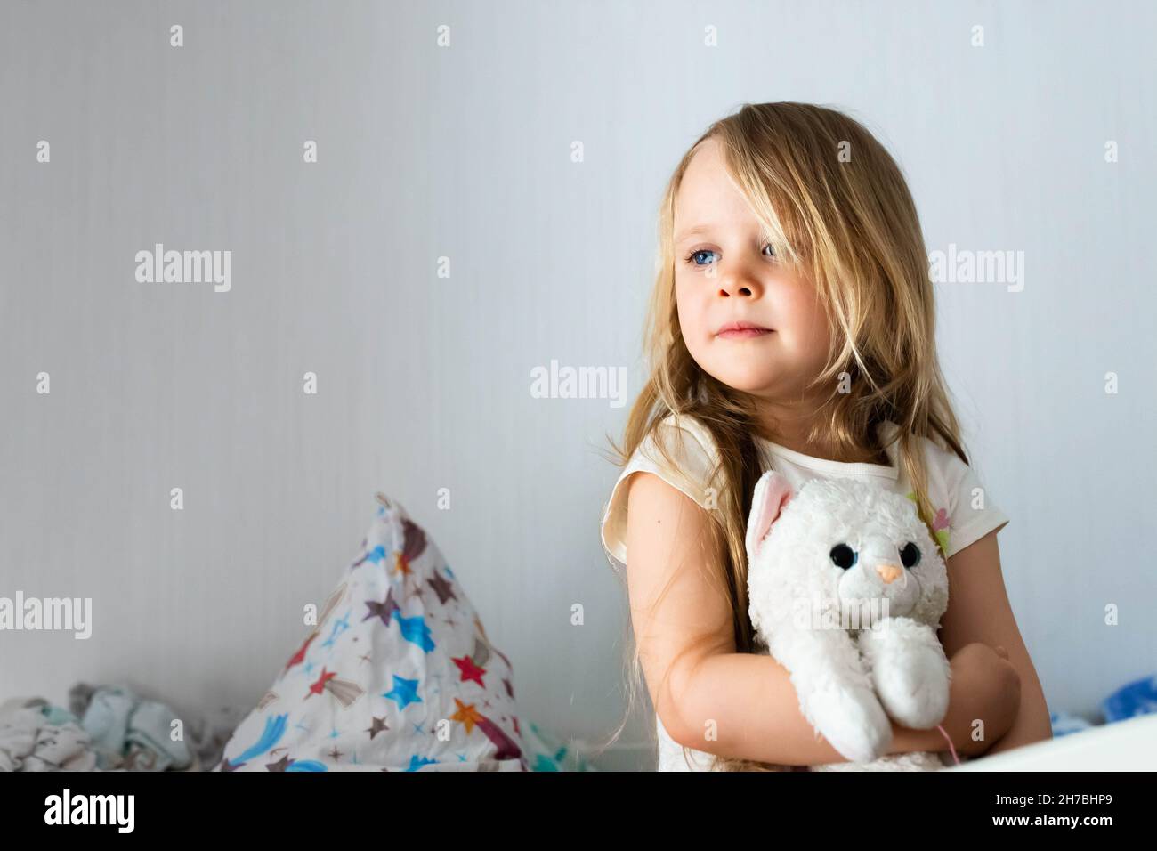 Ritratto di una bambina nella stanza dei bambini che abbraccia un giocattolo. Sorridendo sullo sfondo della camera. Foto Stock