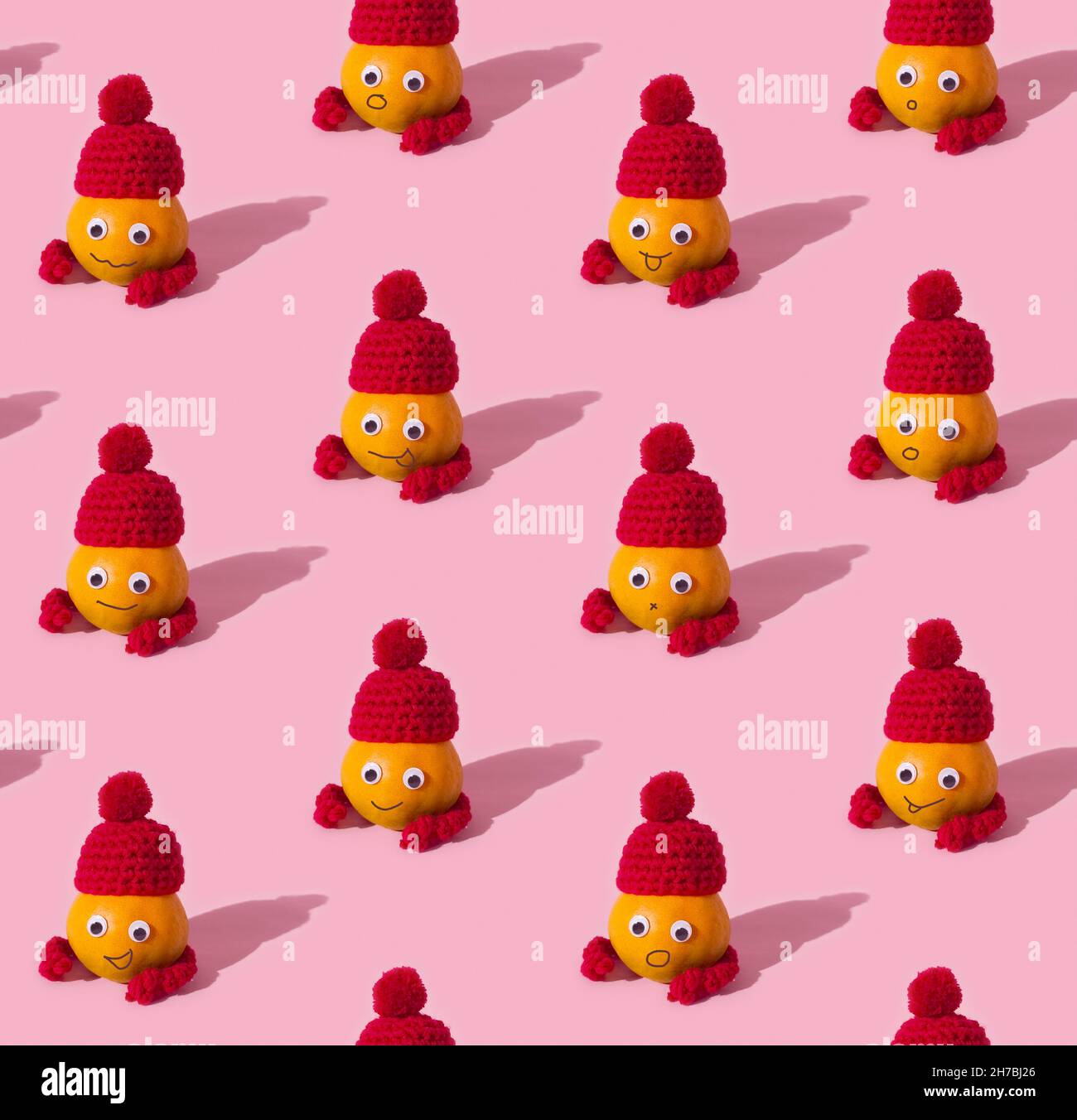 Frutta modello senza cuciture di simpatici tangerini in cappelli su sfondo rosa Foto Stock
