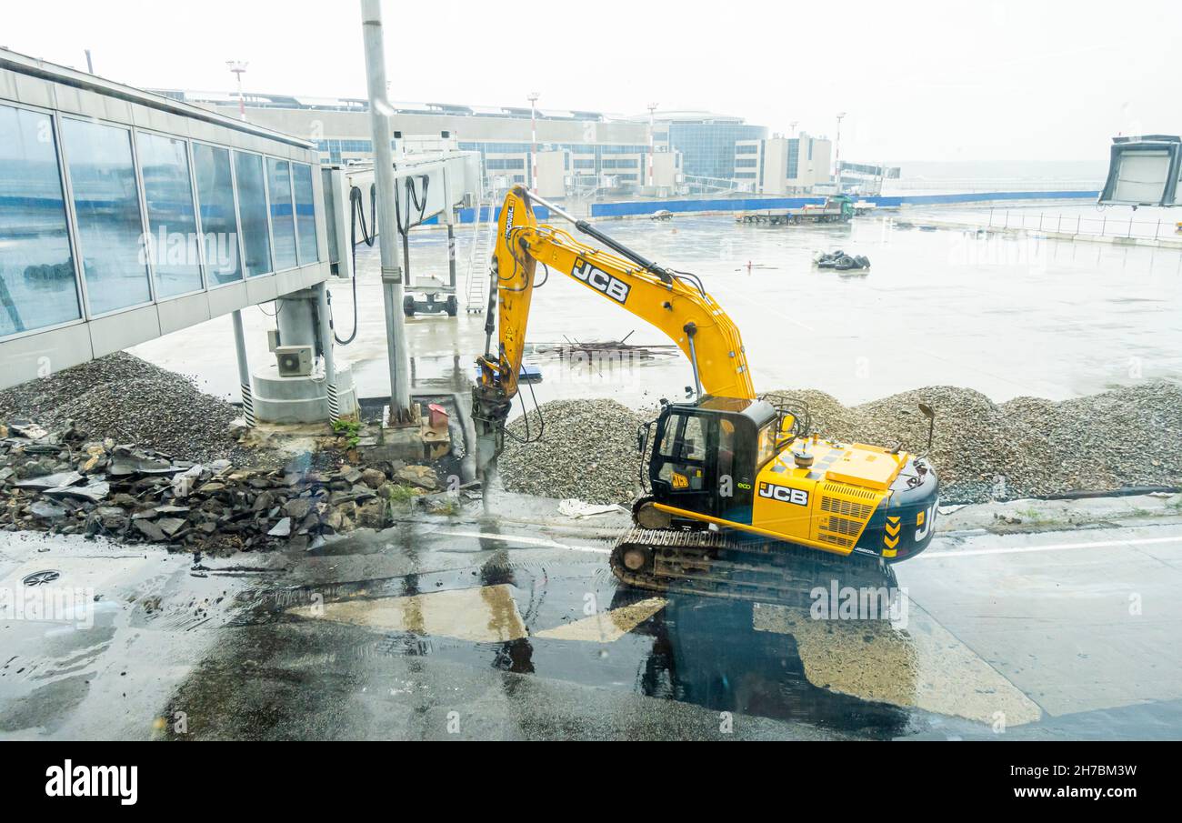 JCB macchina escavatore idraulico a martello frantumazione pavimentazione durante i lavori di ristrutturazione a Domodedovo International Airport, DME, Mosca, Russia Foto Stock
