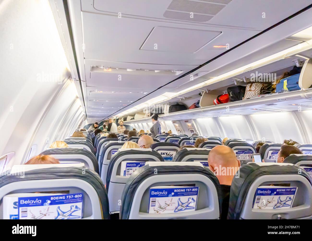 Passeggeri seduti in sedie e che camminano verso una cabina di un aereo  Belavia Boeing 737-800. Imbarco su un aereo da Belavia Foto stock - Alamy