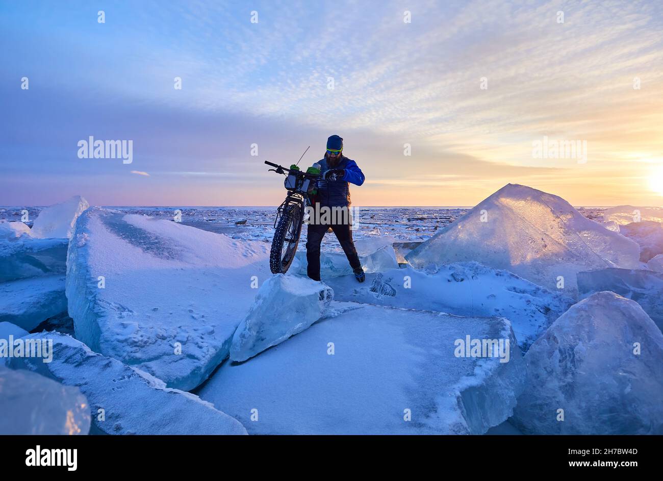 Uomo con bici grassa sul lago ghiacciato Kapchagay al tramonto in Kazakhstan Foto Stock