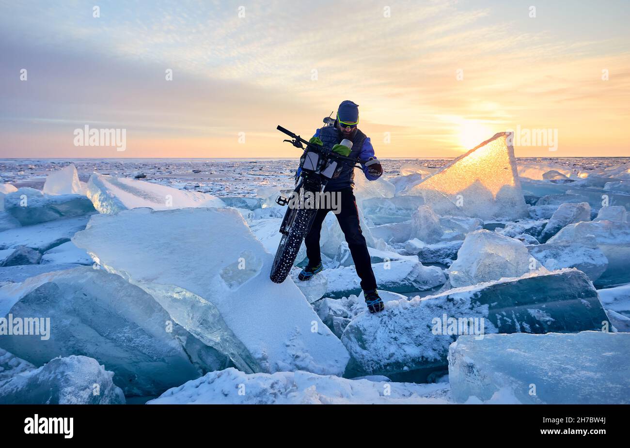 L'uomo si gira a Fat bike sul lago ghiacciato Kapchagay al tramonto in Kazakistan Foto Stock