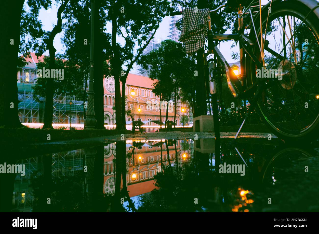 Incredibile riflessione specchio attraverso il laghetto dopo la pioggia, sosta in bicicletta nel parco con parete rossa sfondo della cattedrale di Notre dame e riflettere sull'acqua al crepuscolo Foto Stock